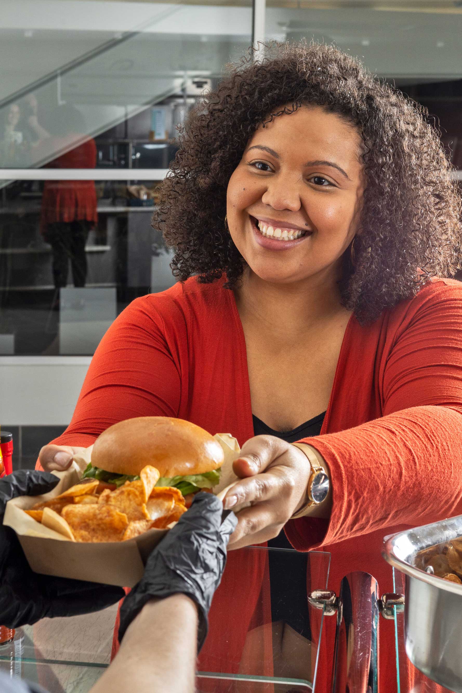 Customer smiling while reaching for sandwich and chips